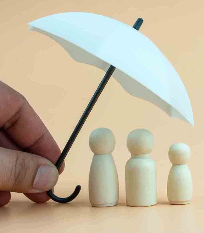 White umbrella with wooden family peg dolls for protection with copy space. Family protection and insurance coverage concept. The insurance agent presents protection model that symbolize the coverage.